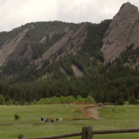 People in the distance walking a trail toward Boulder's Flatirons