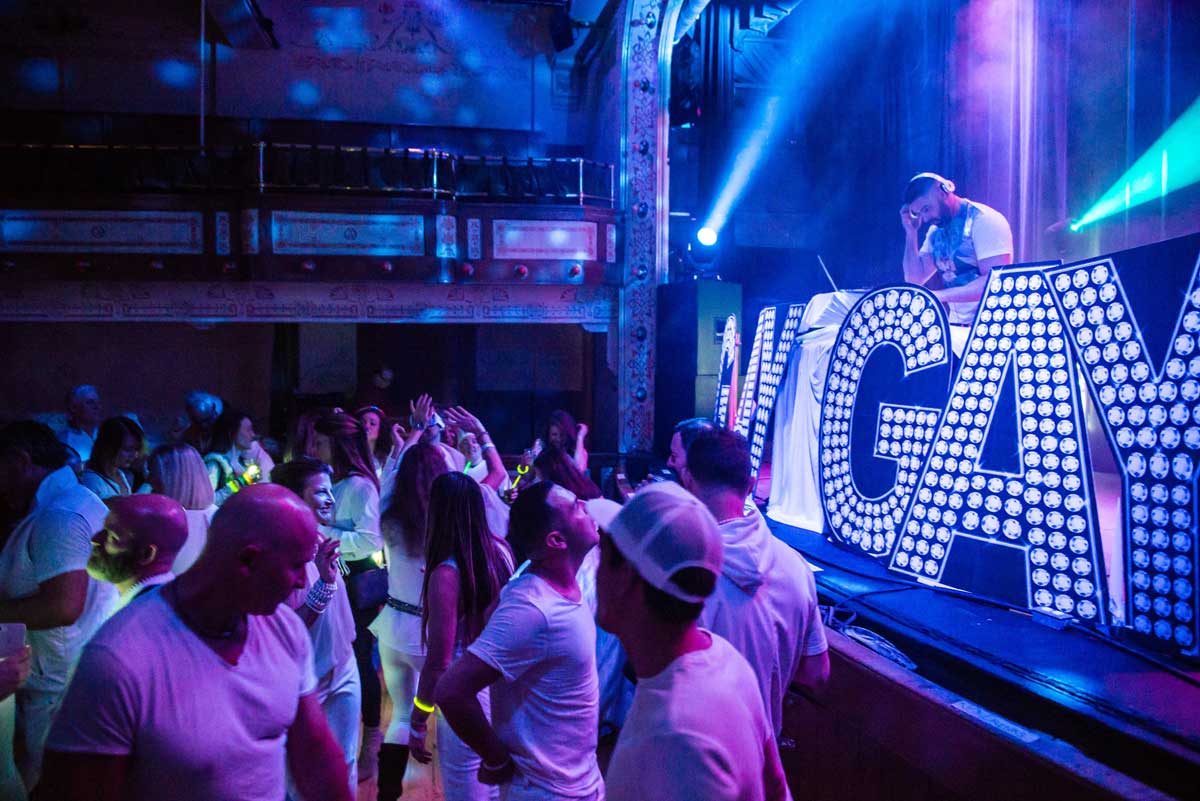 Telluride Gay Ski Week attendees dance to live DJ music under blue and green lights
