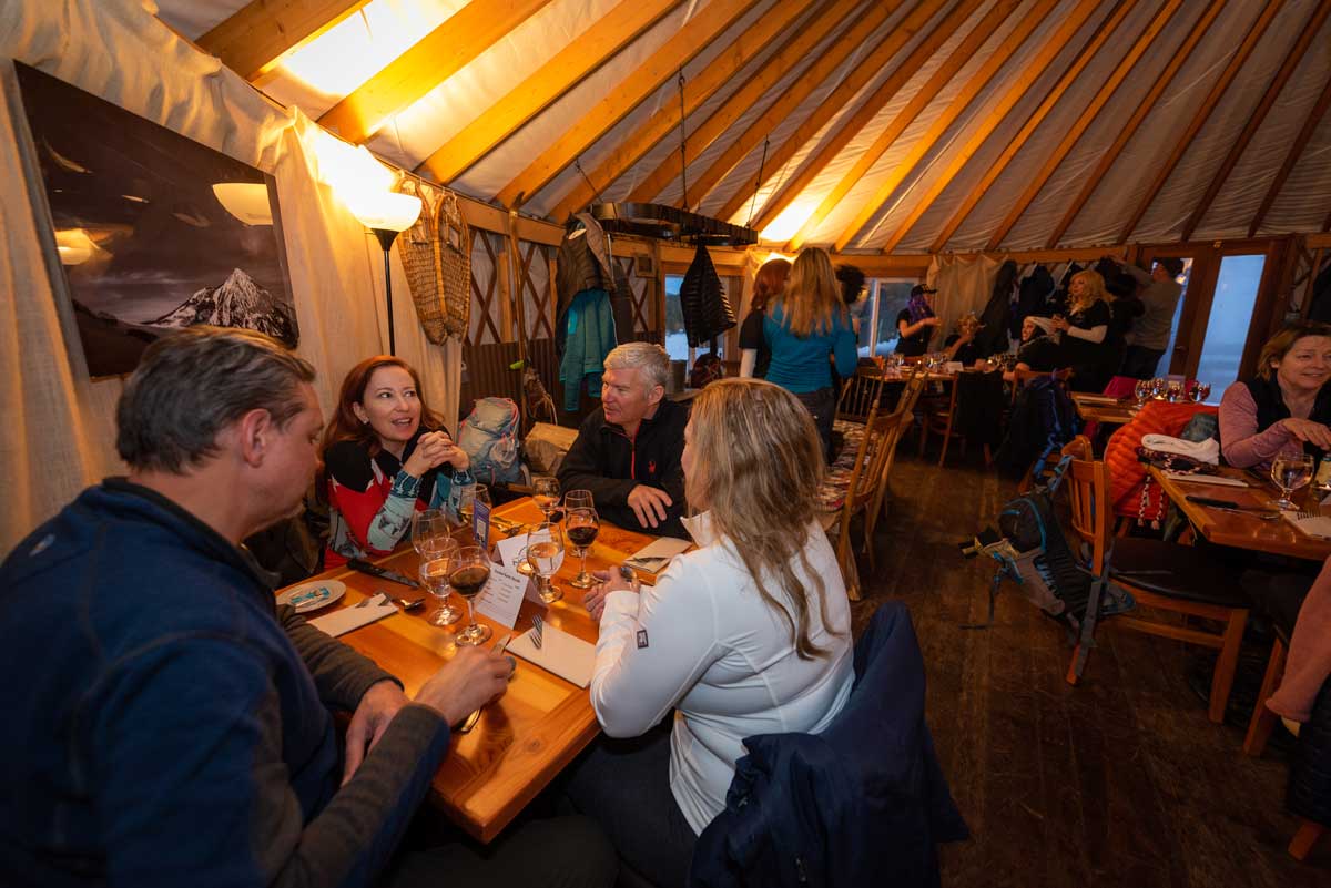 Group of people eating dinner inside a yurt with glowing lights