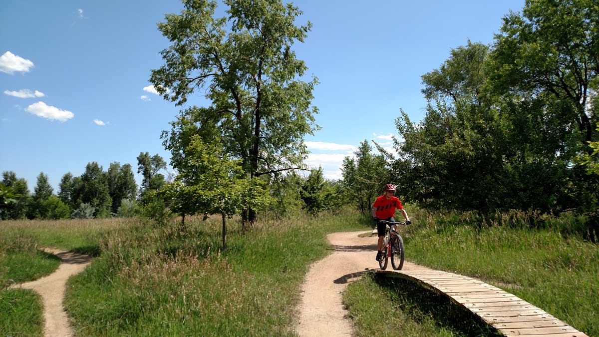 A person on a bike rides over a wooden ramp