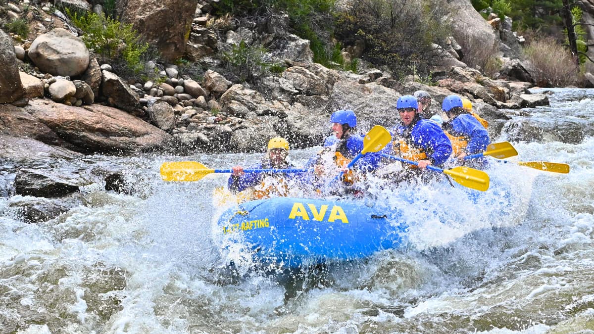 A group of five people gets splashed by the white-capped waves on a whitewater rafting trip with Arkansas Valley Adventures Rafting & Zipline.