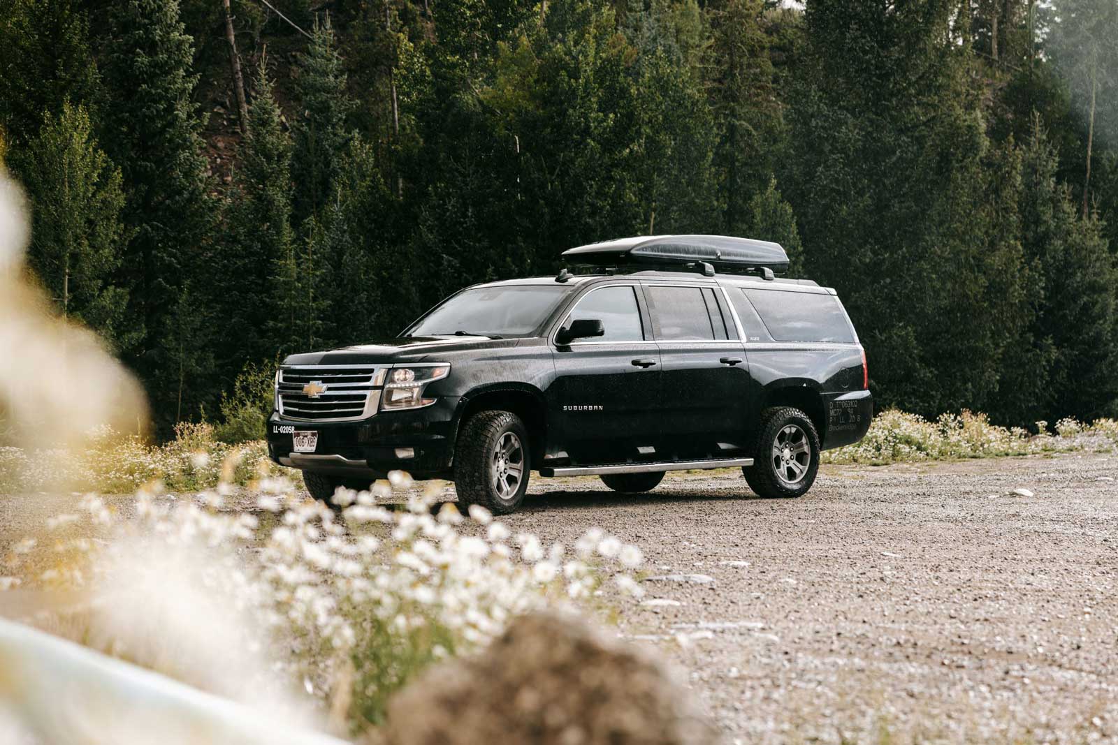 A black SUV is parked beside a scenic roadway