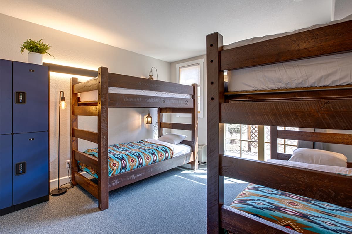 Two bunk beds made of thick, dark wood face each other across a white-painted room in Colorado.