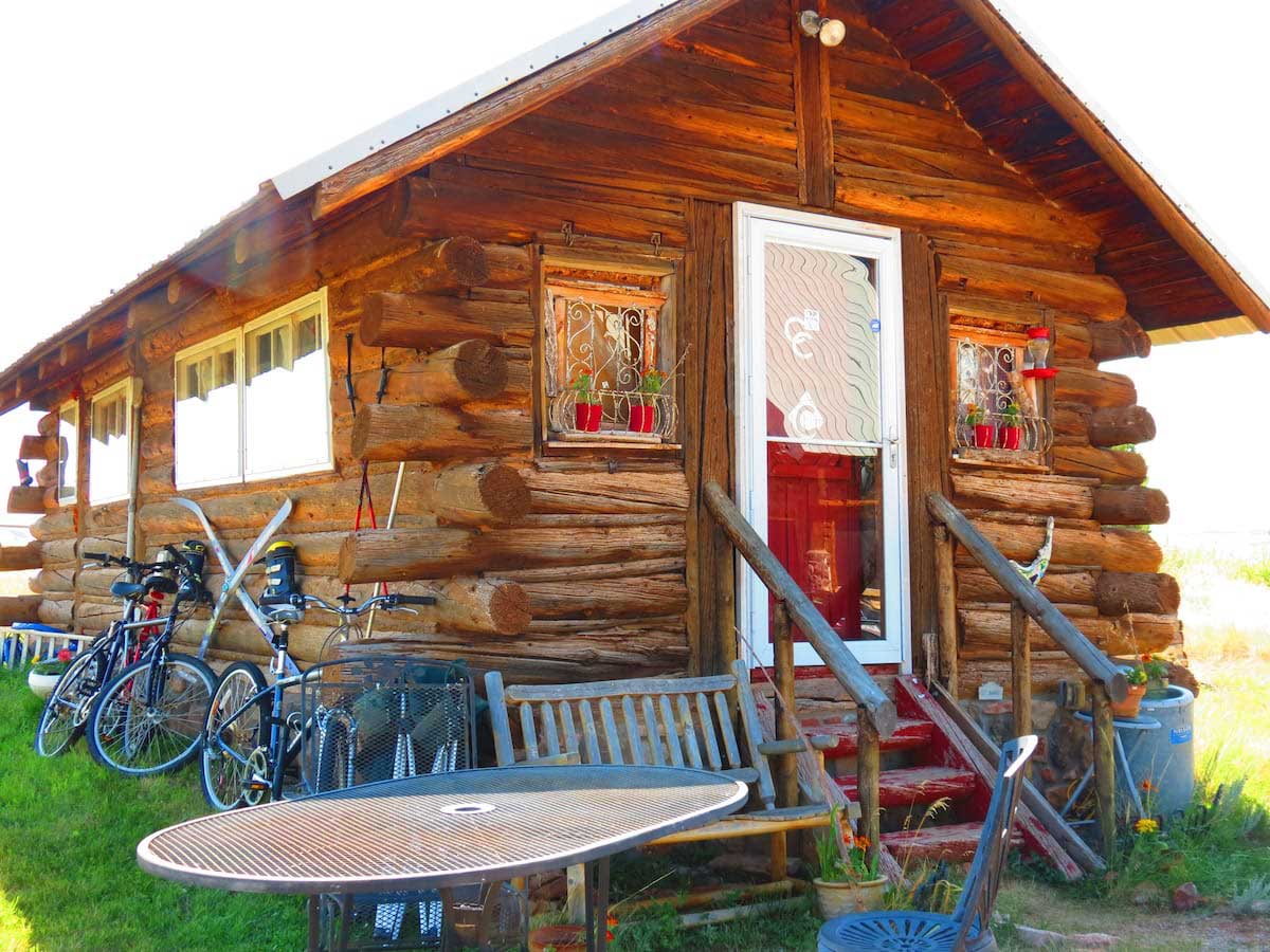 Colorado Cabin Escape looks quaint and peaceful. The sun shines in the sky above the cabin.