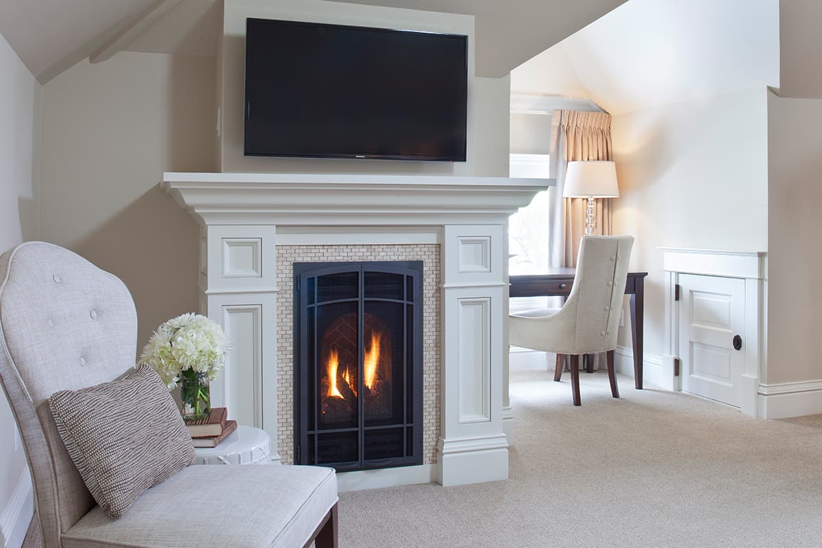 A stately fireplace with a crackling fire, stands in a modern beige and white decorated room at Edwards House in Fort Collins.
