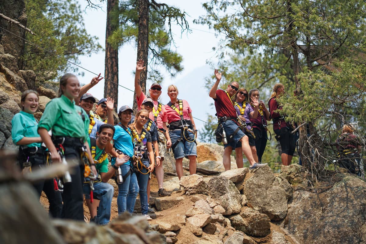 Soaring rangers and happy guests waving, prepping for a zipline adventure.