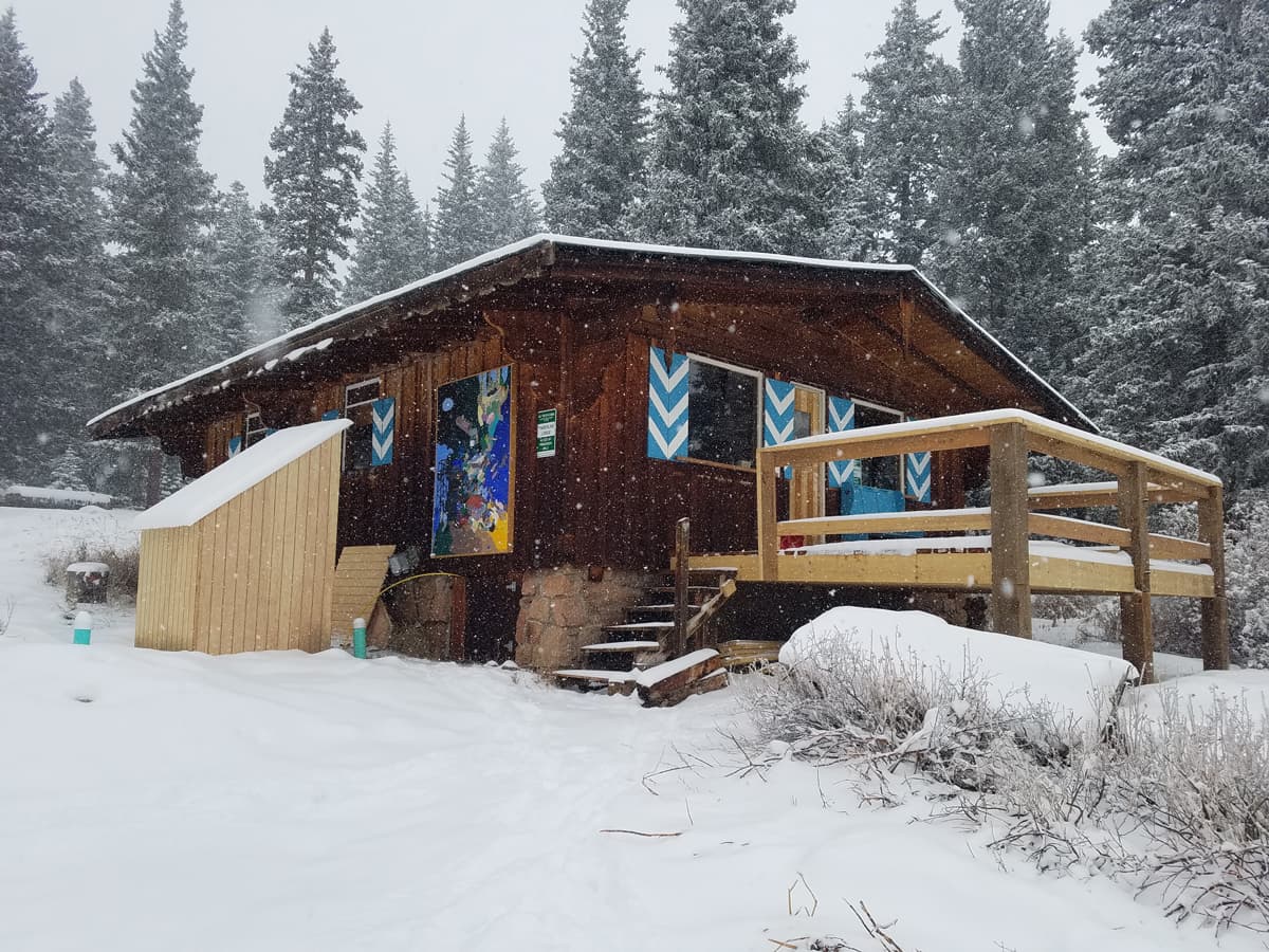 One of the nine backcountry huts Colorado Adventure Guides has access to, surrounded by snow-flocked evergreens and blankets of fresh powder.
