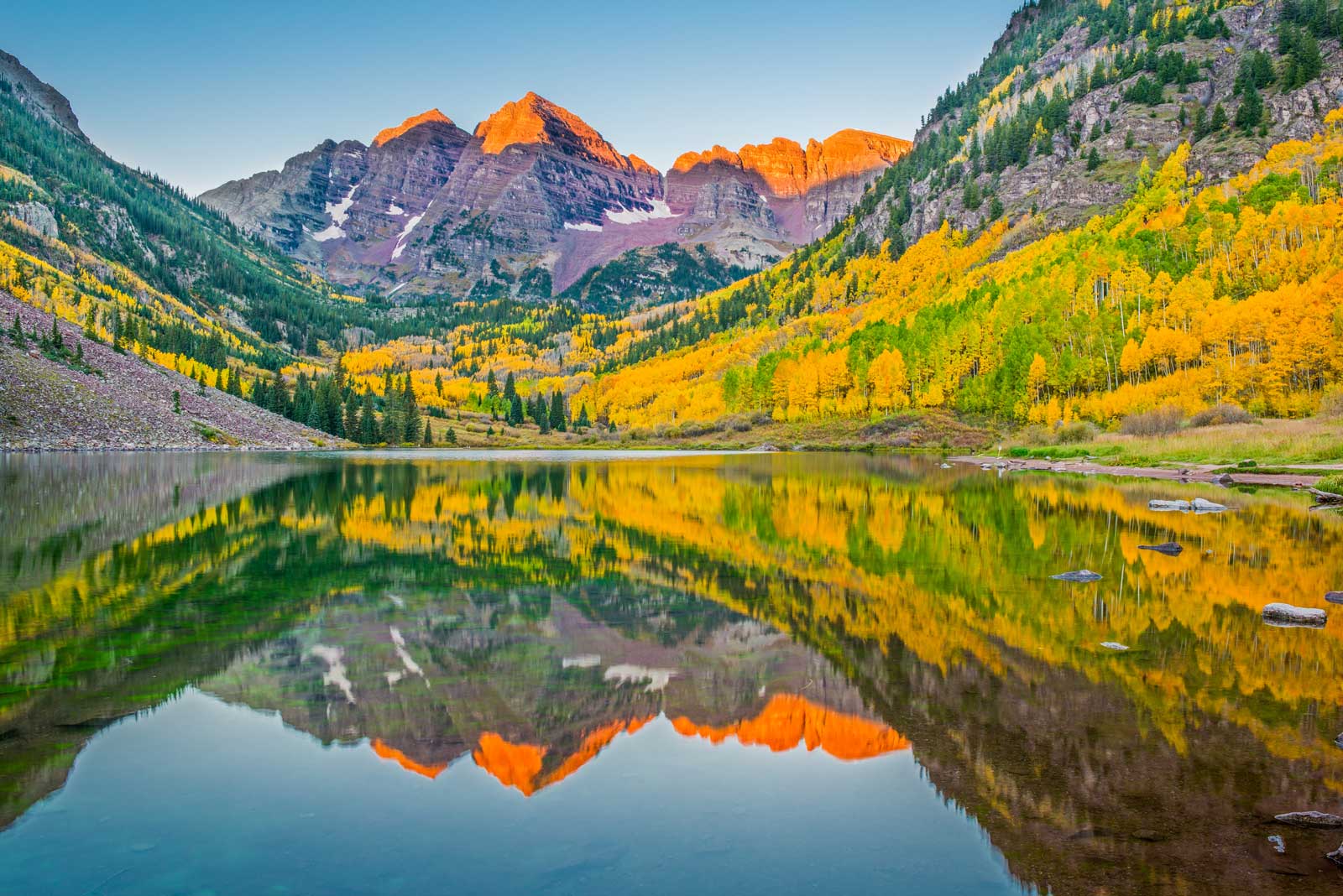 The bell-shaped peaks of the Maroon Bells surrounded by yellows and greens of all leaves