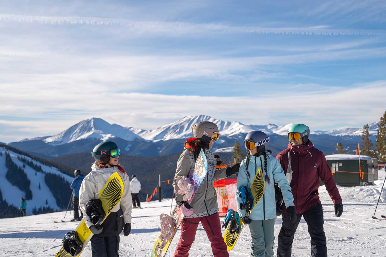 Four skiers and snowboarders walk along the ski slope in Keystone