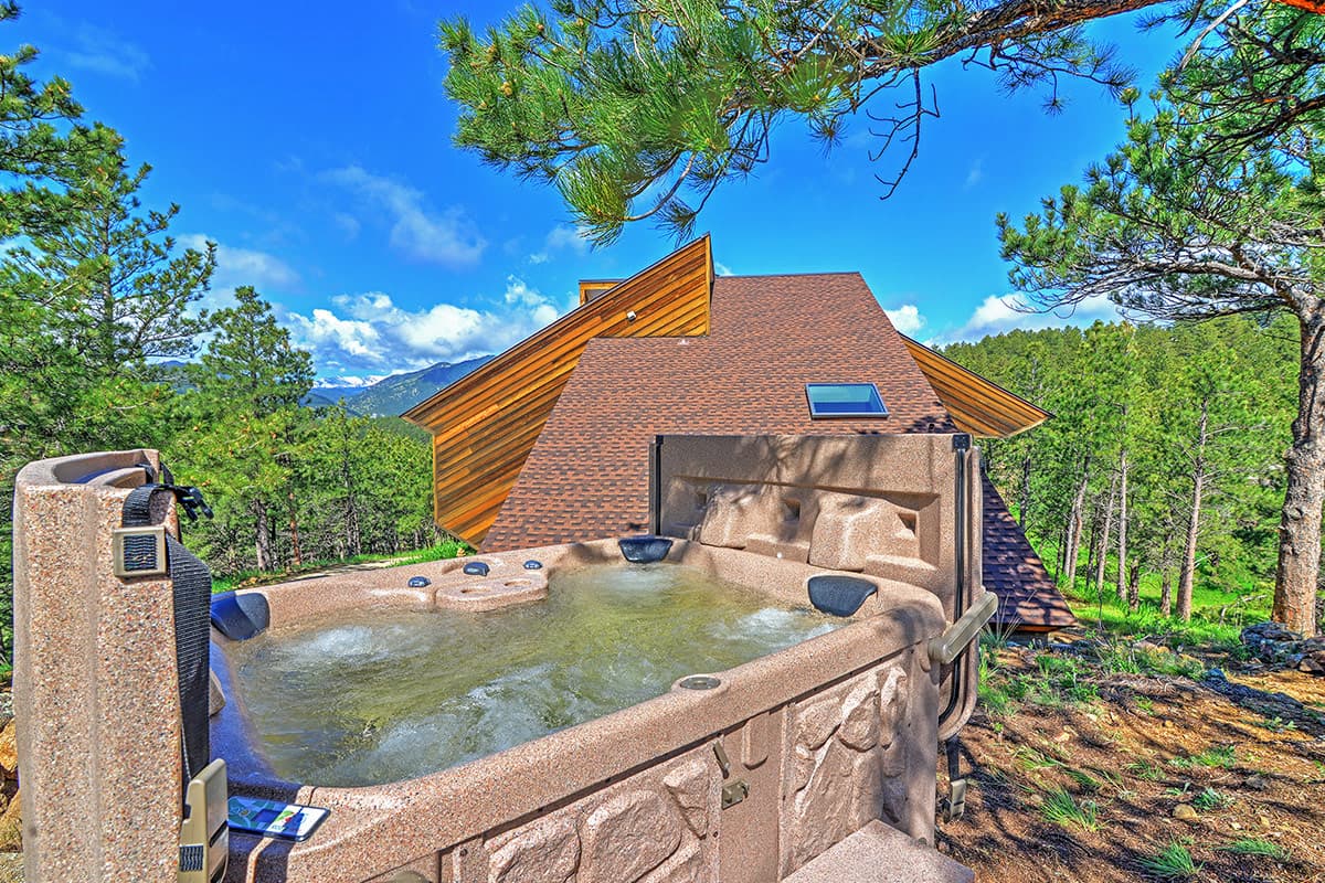 A rooftop hot tub at Barret House near Boulder, Colorado, offers stunning views of the mountains, forest and clear sky.