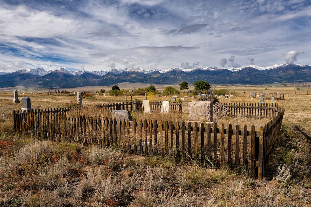 Cemetery field with close-up view of a small area with wooden fences forming a square, with gravestones inside it.