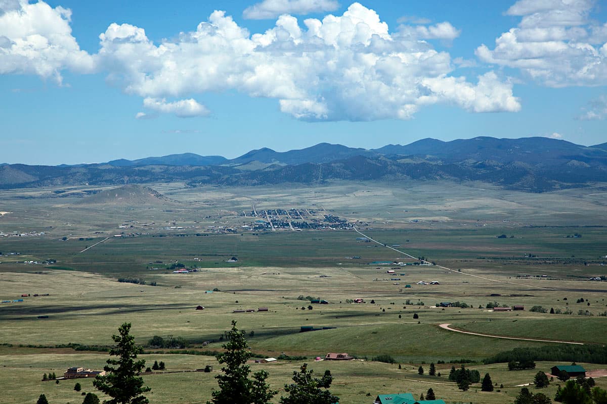 Daylight far away views of a green valley with mountains far away standing tall.