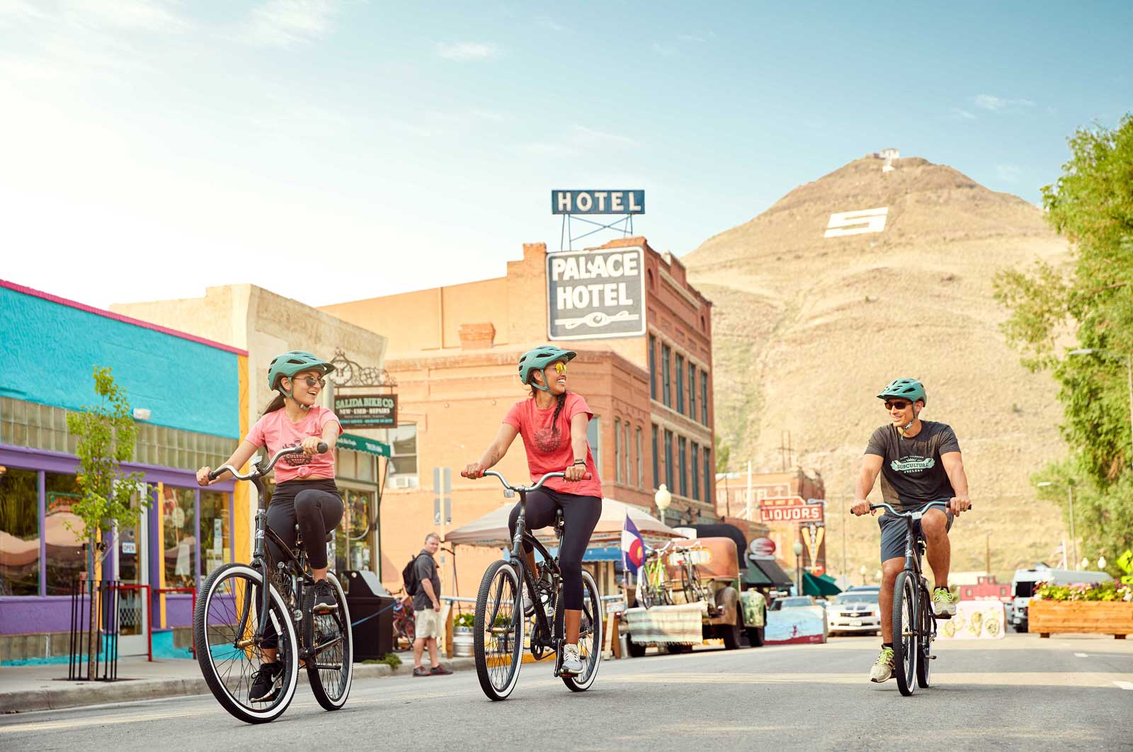 Three people ride cruiser bikes down the street in the Salida Creative District