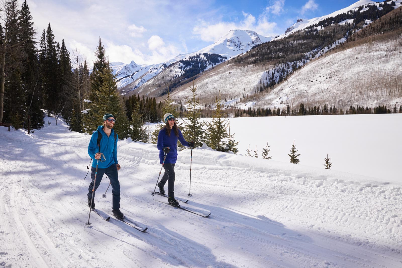 Two people cross-country ski on a groomed track in Ouray