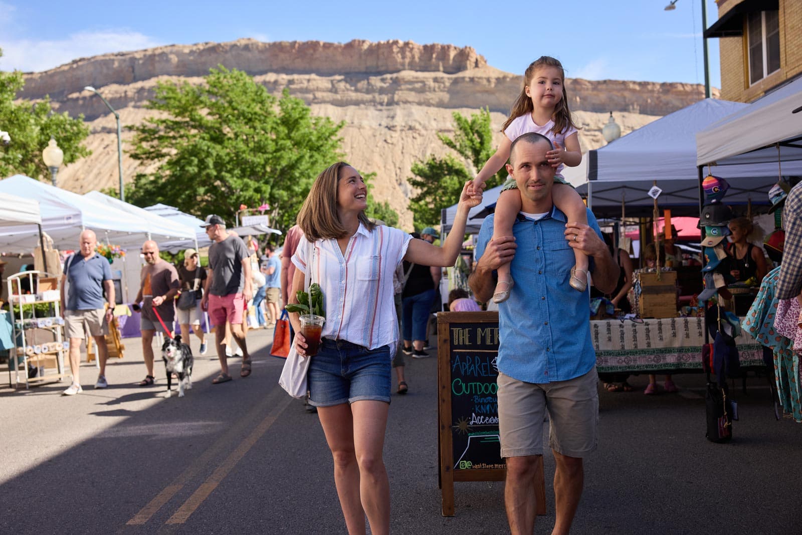 A family walks thorugh the stalls at a Colorado farmers market in Palisade