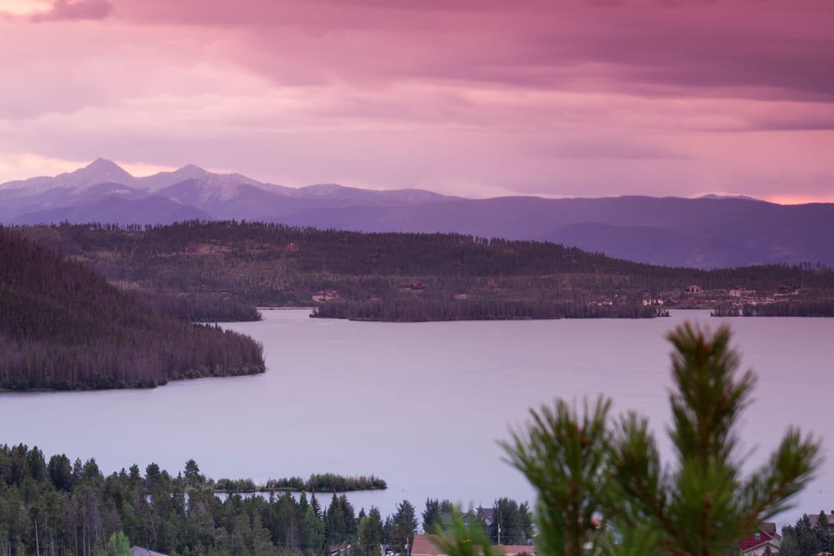Sun setting over a mistly lake at dusk with mountains behind it