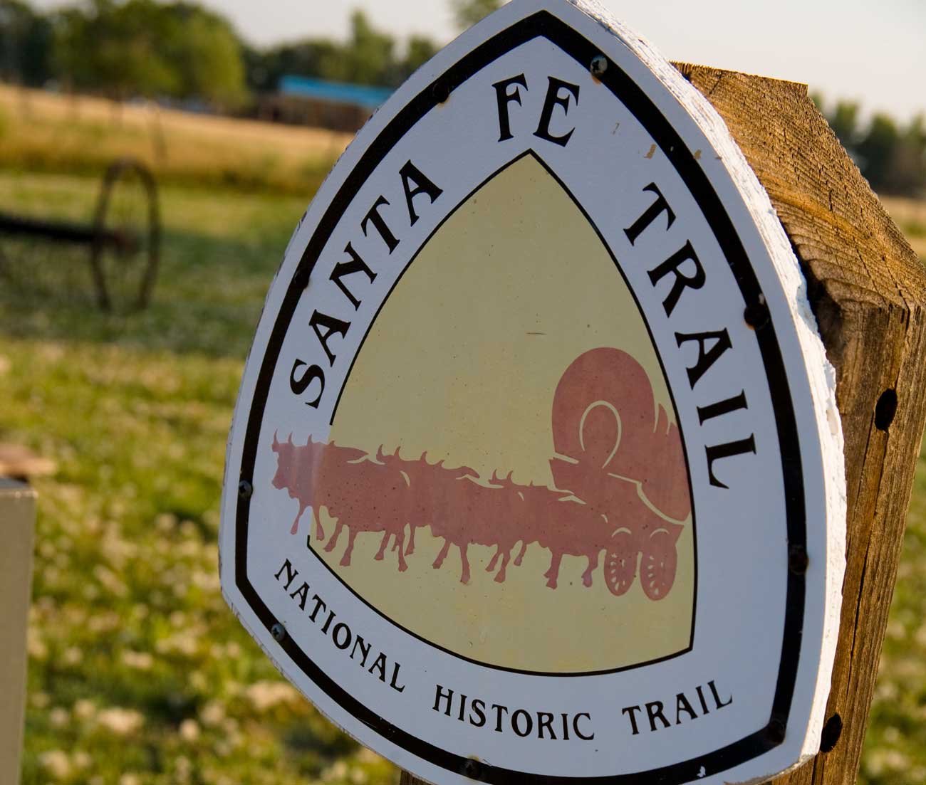 A triangle trail marker reads "Santa Fe Trail" on a summer's day.