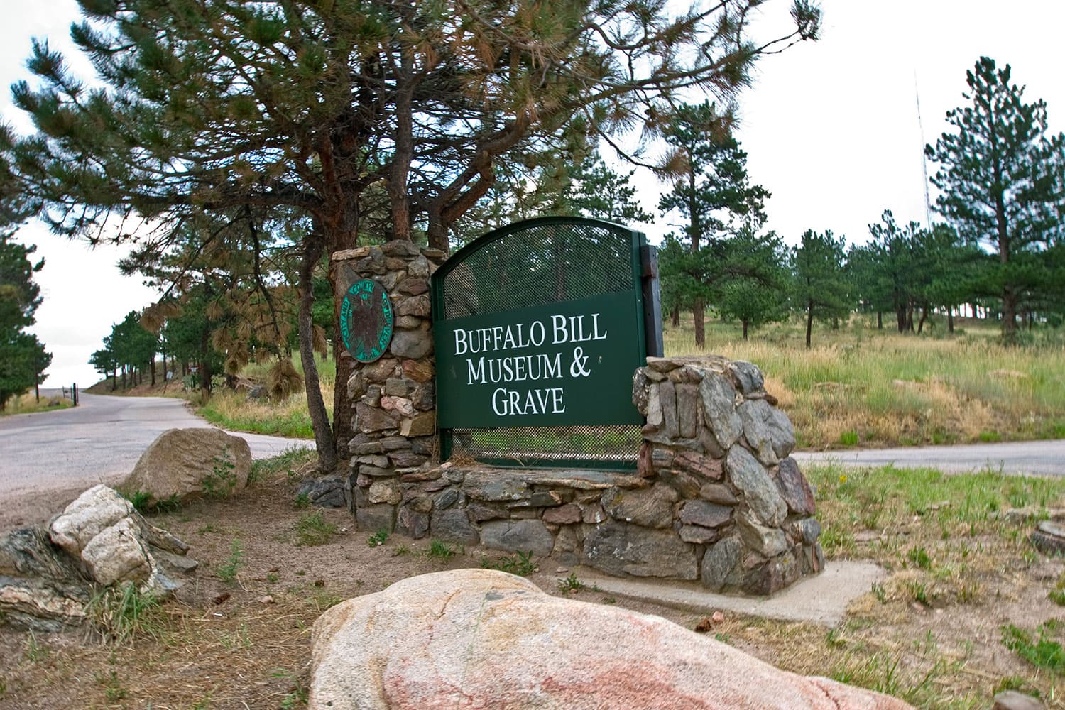 A green sign with a gray-stone base marks the entrance to the Buffalo Bill Museum & Grave near Golden, Colorado.