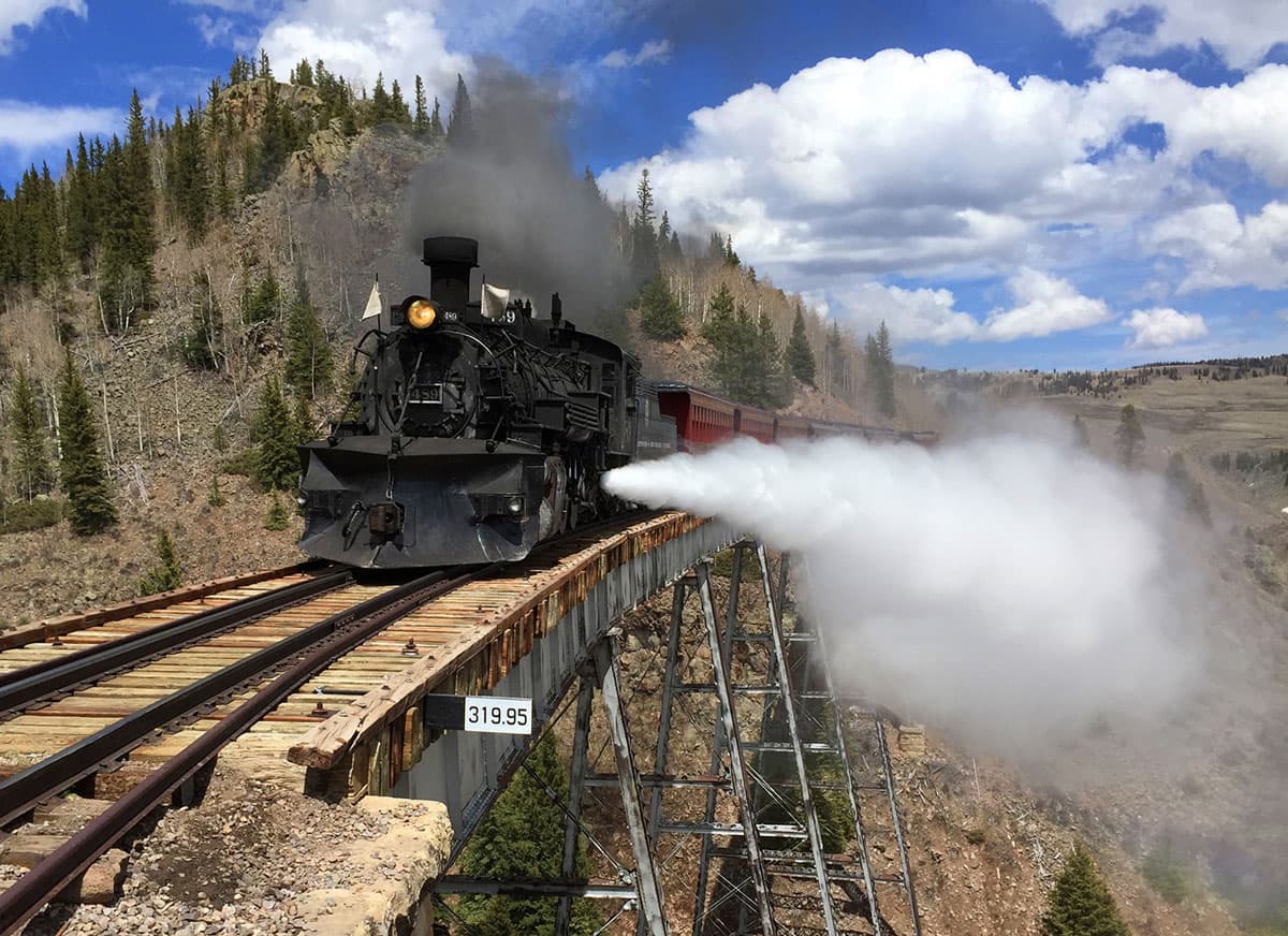 A train moves across a high mountain trestle