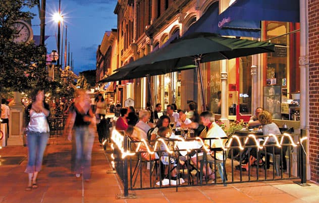A busy sidewalk and outdoor eating area on a summer night in downtown Denver on Larimer Square.