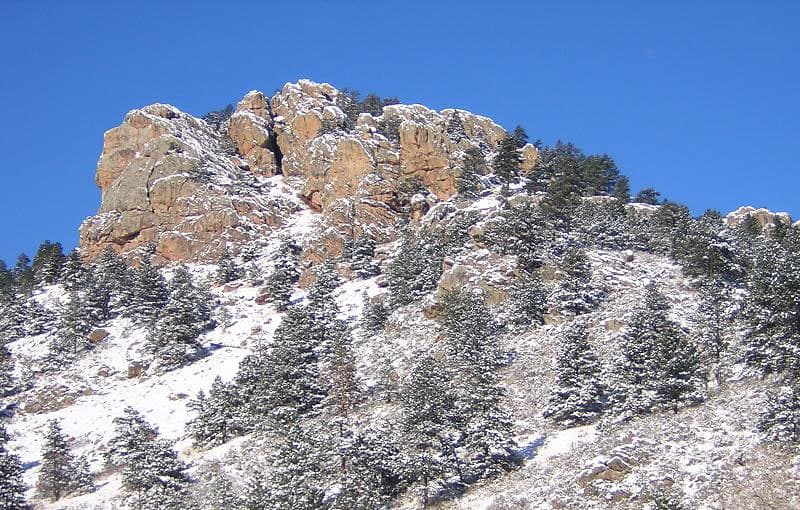 A snow-dusted ridge with frosty trees surrounding its slopes