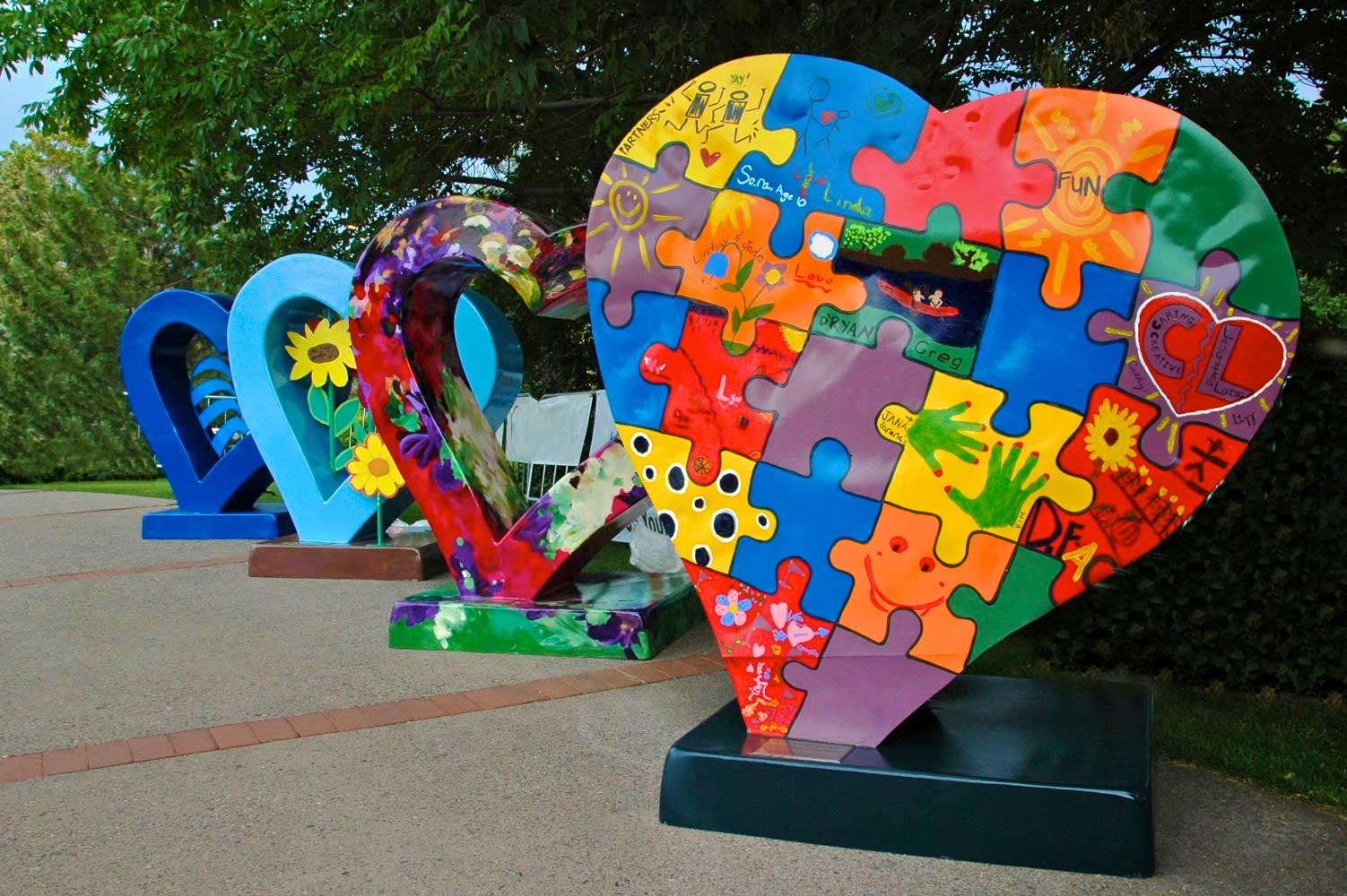 In Loveland, Colorado, four people-sized hearts statues are set in a diagonal line. Each heart is decorated differently, some have flowers or dark colors and others feature a puzzle design.