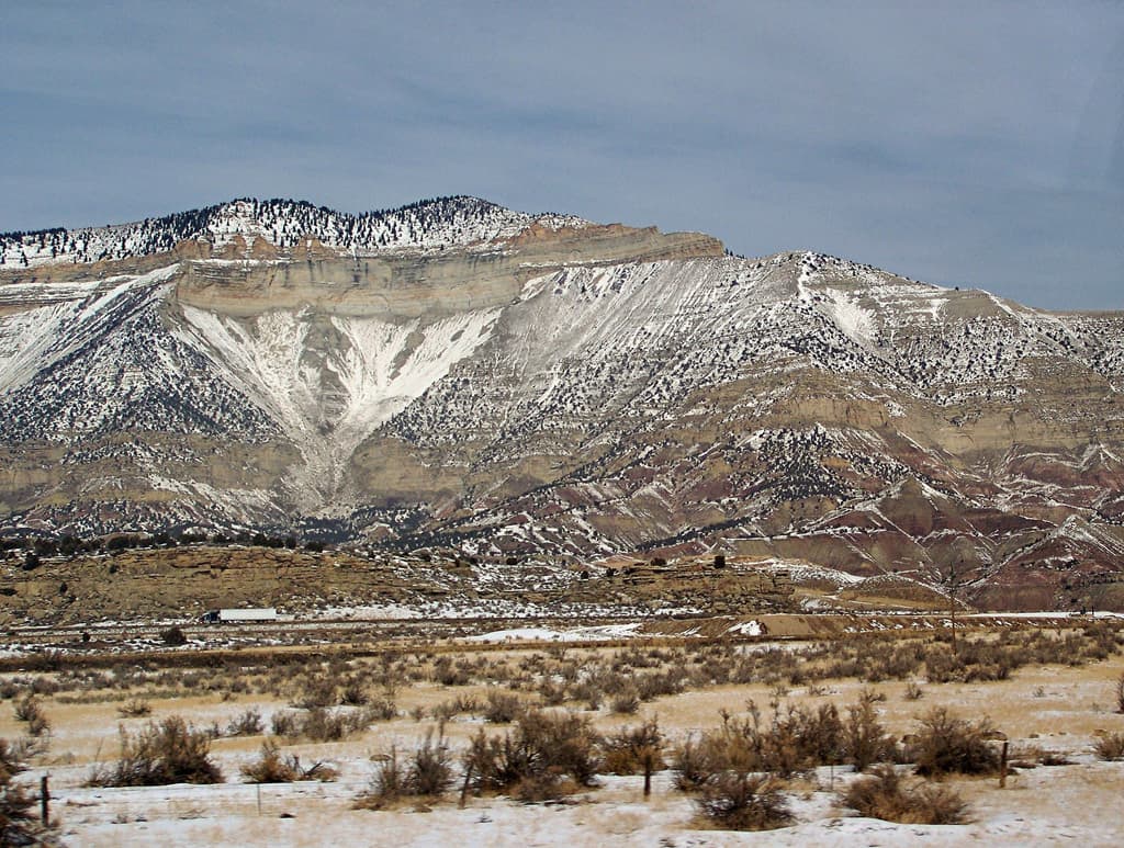 The snow-covered book cliffs sit above Parachute with grey-blue skies up above.