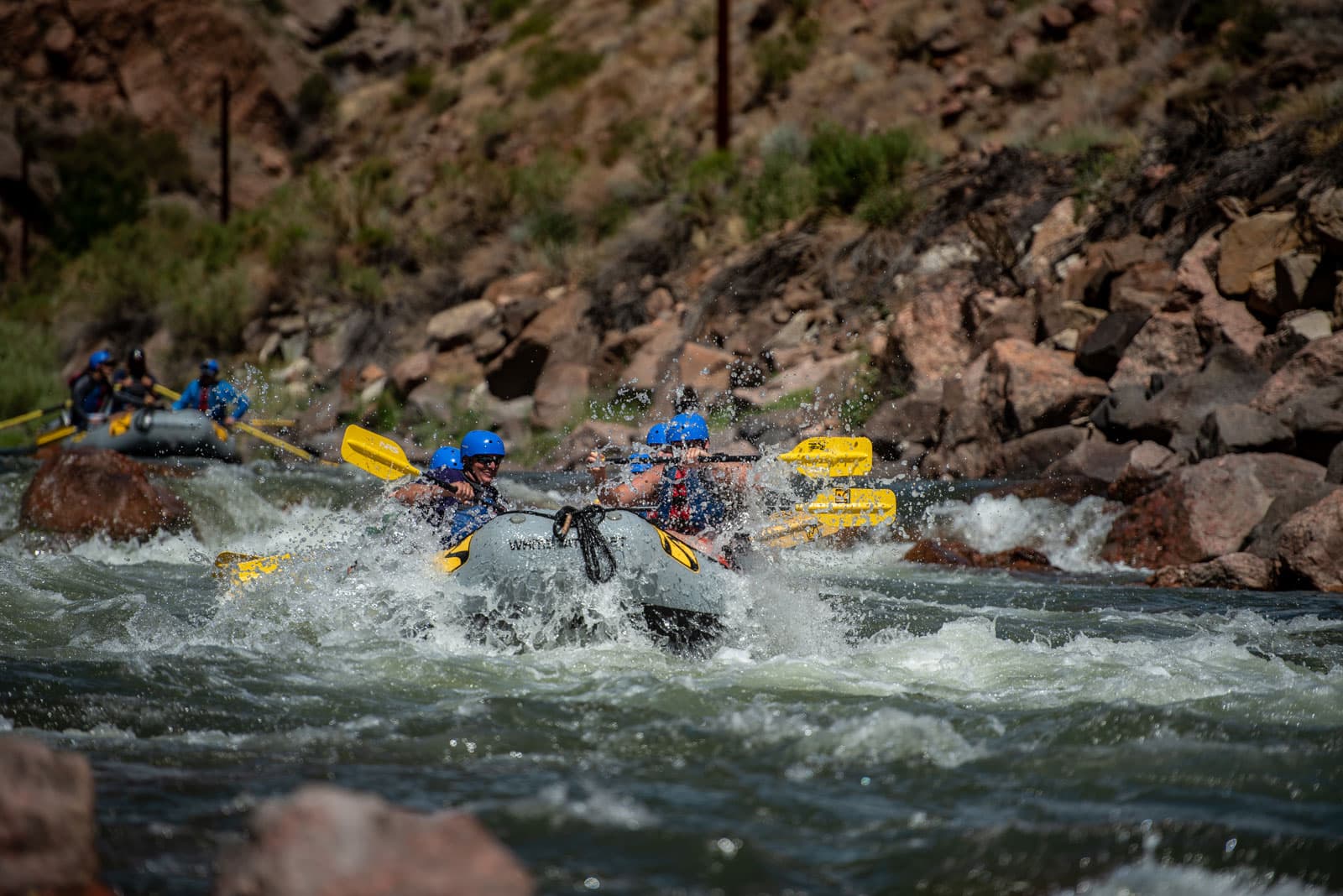 A raft full of paddlers navigates the waves and rocks