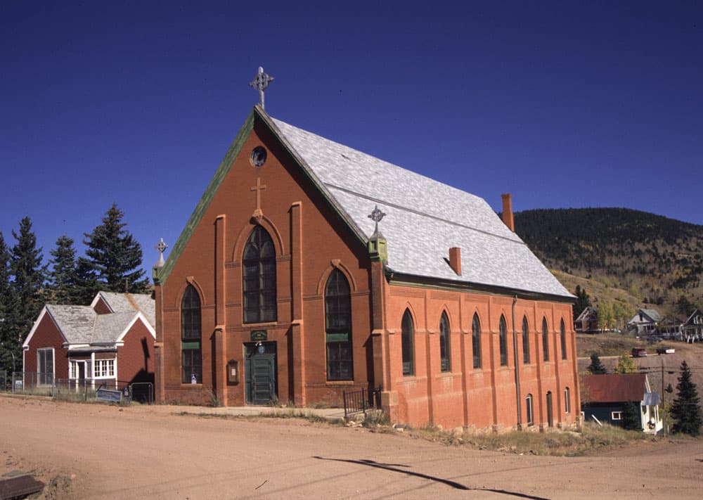 The Richardson-Romanesque St. Victor's Catholic Church sits on a dirt road with a deep-blue sky up above.