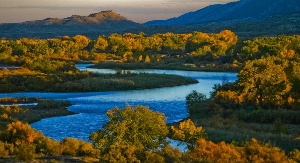 A river weaves its way through a landscape accented by the beginning of fall colors near Grand Junction.