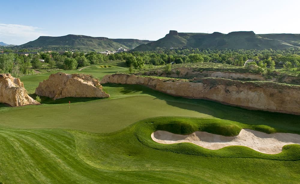 A lush green golf course with mountains in the background