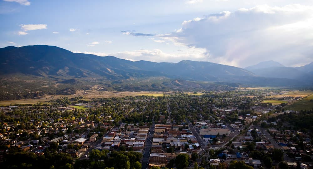 Aerial view of a town tucked in a valley with large mountains in the background
