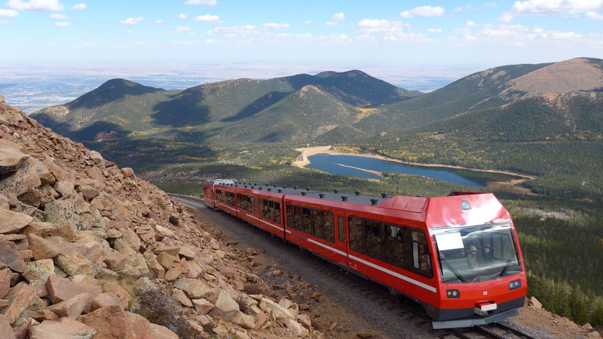 Pikes Peak train with alpine lake and mountains in the background