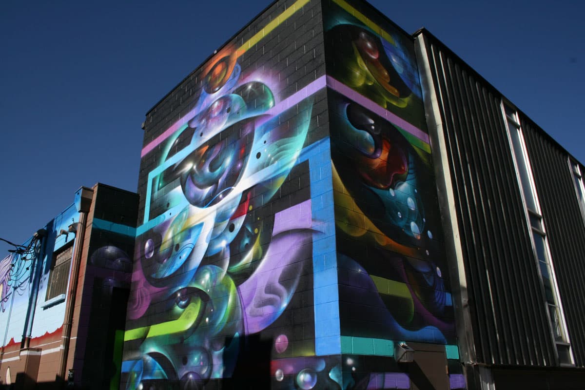 A colorful mural featuring spheres and thick lines stands out on the side of a building in Denver's RiNo neighborhood.