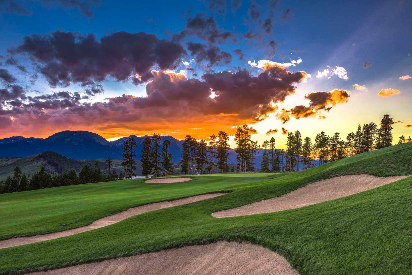 The sun sets over a mountain golf course