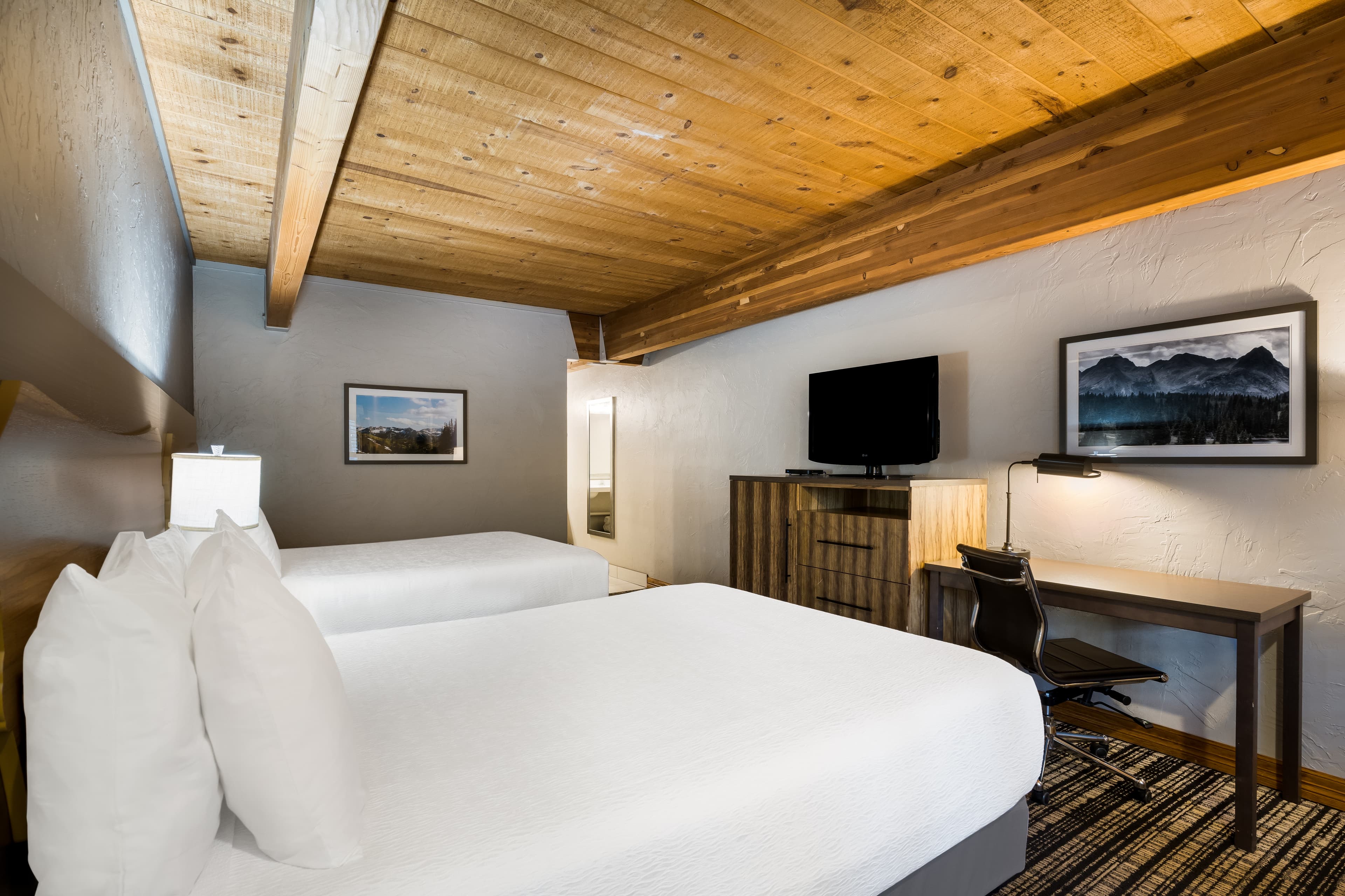 A hotel room with comfy white bedding and warm, exposed wood ceilings at Best Western Antlers in Glenwood Springs, Colorado