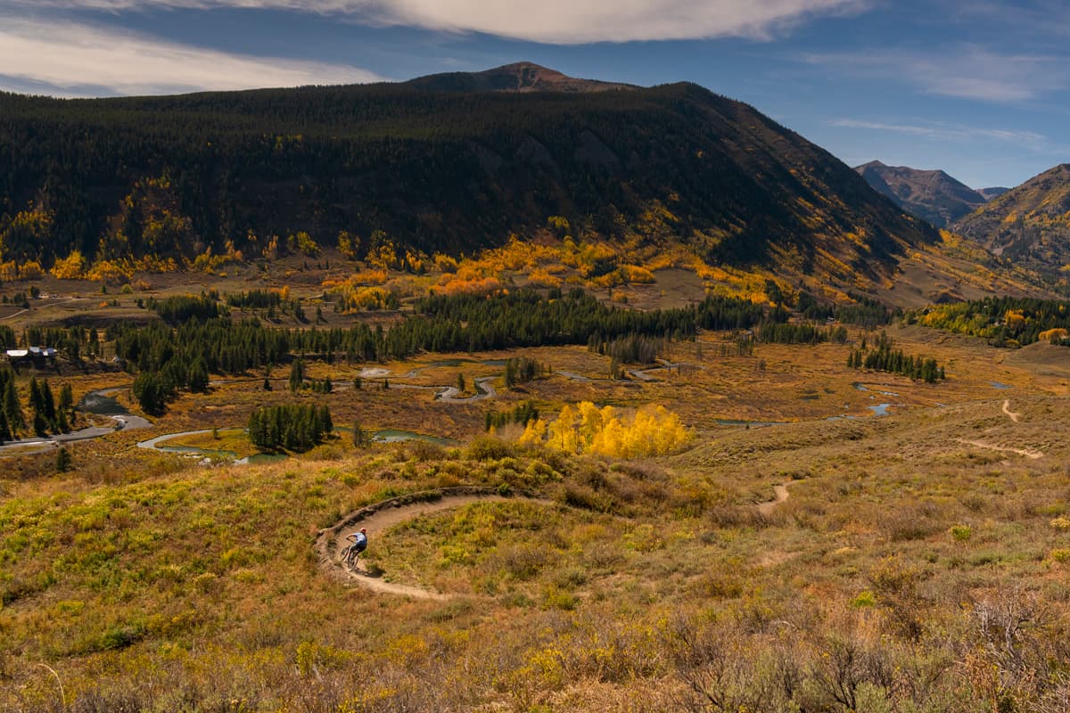 A mountain biker weaves down a windy trail lined with fall colors in Crested Butte, Colorado.