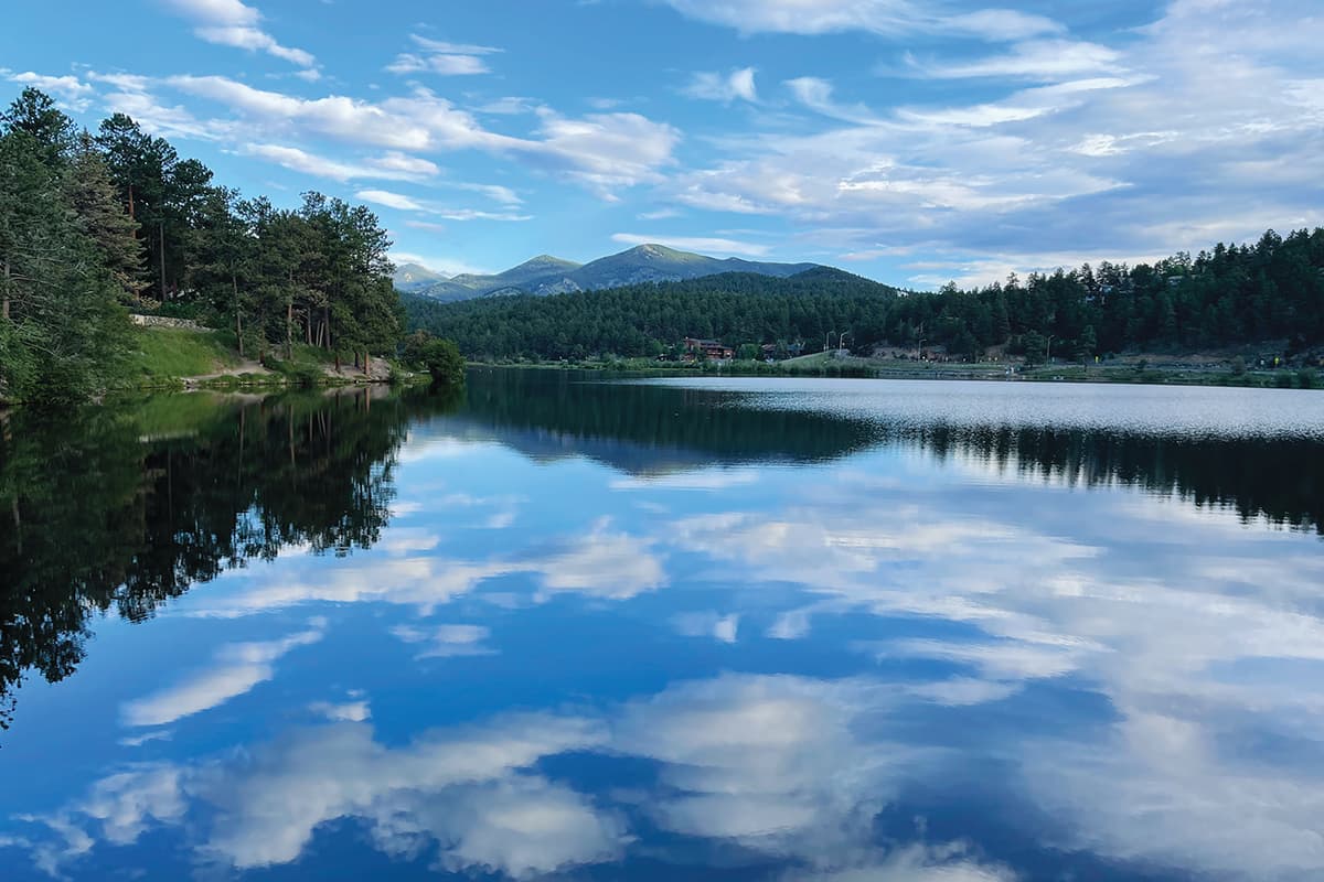 Calm waters of Evergreen Lake, reflecting the sky with tall pine trees surrounding it.