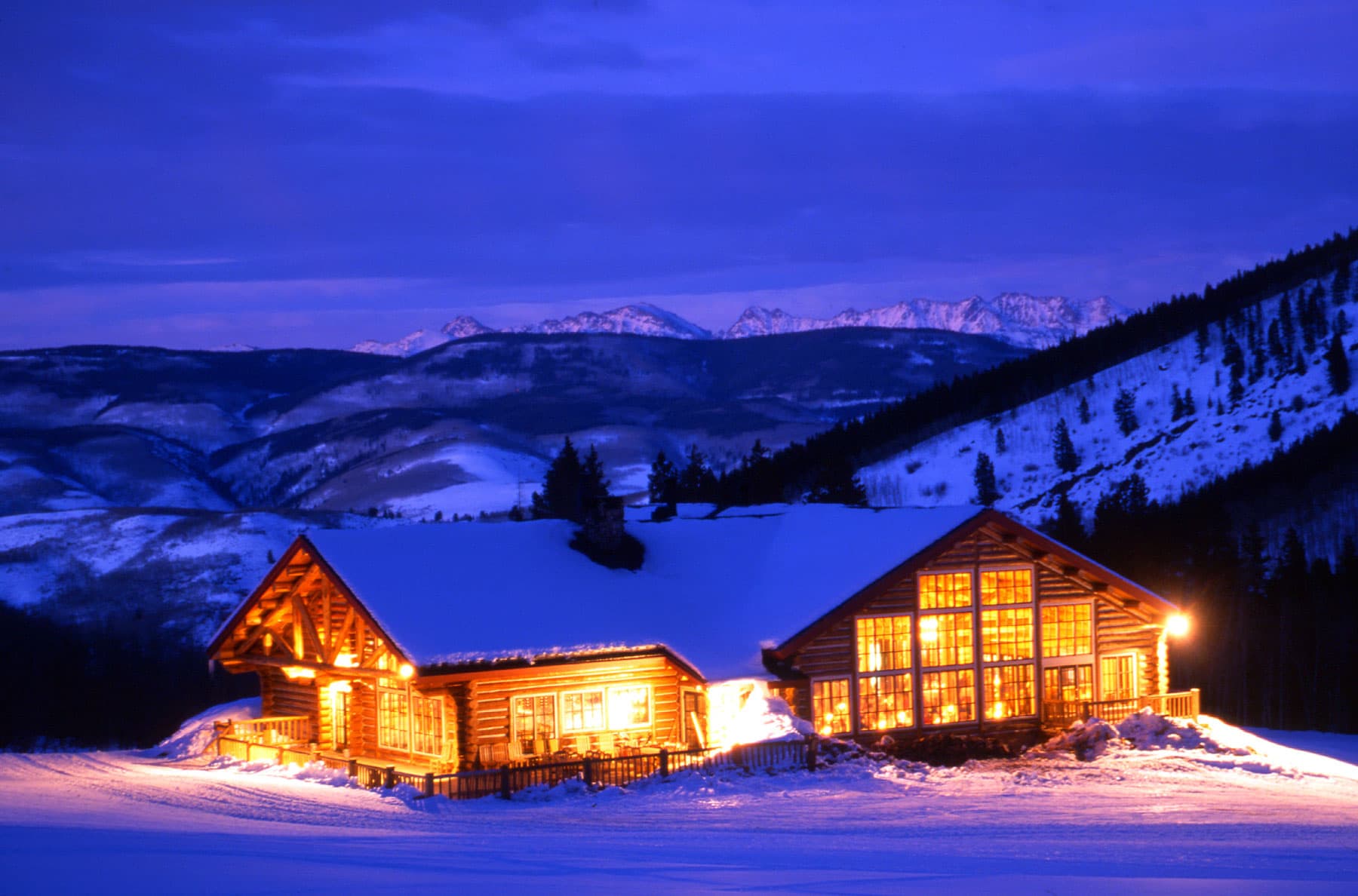 Exterior of Beano's in Beaver Creek Resort, covered in fluffy snow at night, with the windows glowing