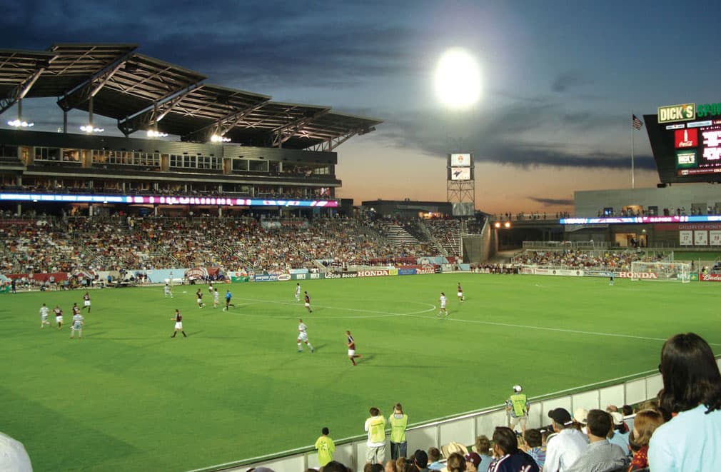 Stadium lights set the green soccer field aglow as fans cheer on the Rapids soccer team in Denver, Colorado.
