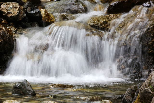 A continuous stream of rushing water tumbles over the different rock levels of the Zapata Falls in Colorado.