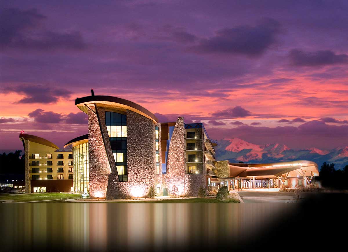 Next to a lake as the sun sets, we see the geometric shape of the casino and hotel