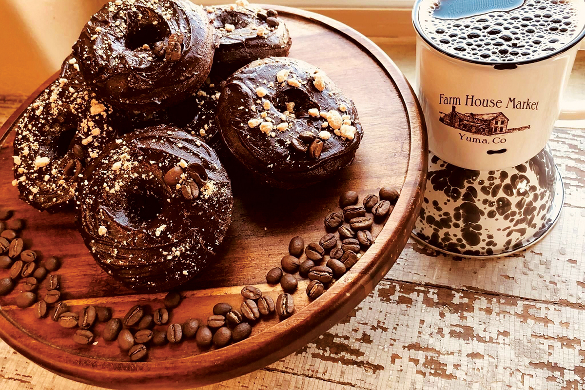 A plate of chocolate-covered donuts with a cup of coffee