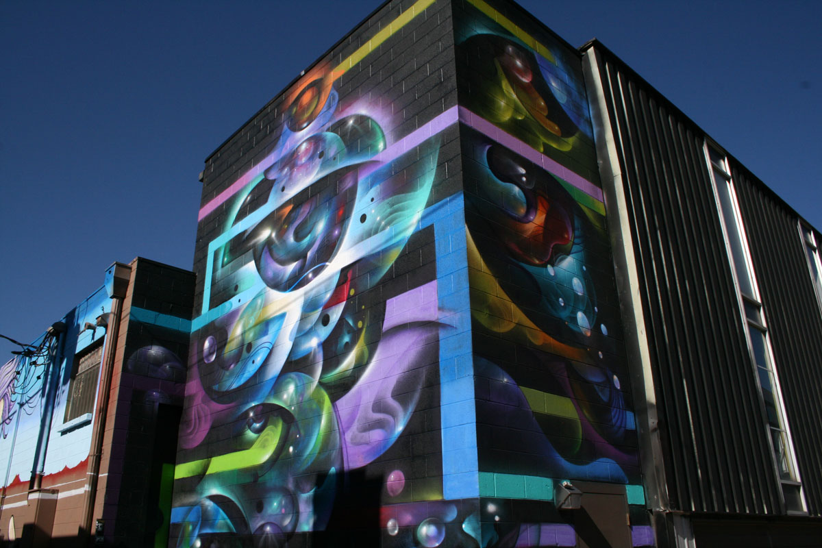A colorful mural featuring spheres and thick lines stands out on the side of a building in Denver's RiNo neighborhood.