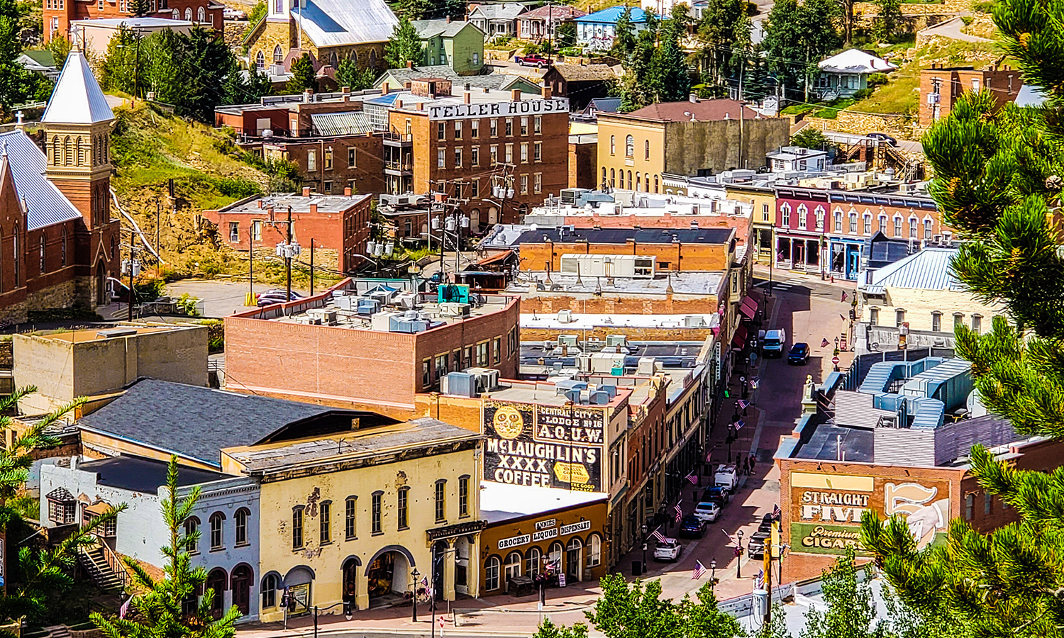 An aerial view of Central City in the summer with green trees, Western storefronts and colorful buildings.