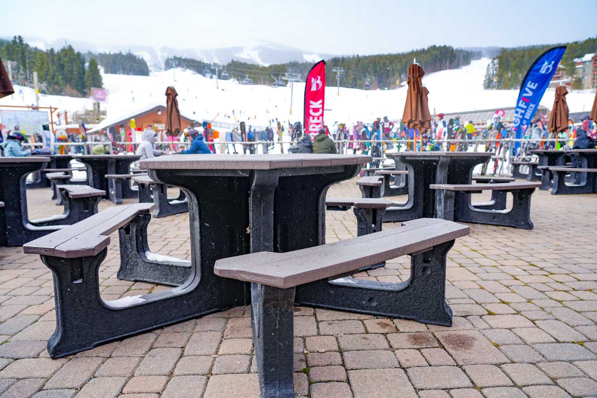 A TerraCycle table made from recycled wrappers stands in the foreground at Breckenridge Ski Resort with the ski runs and diners in the background