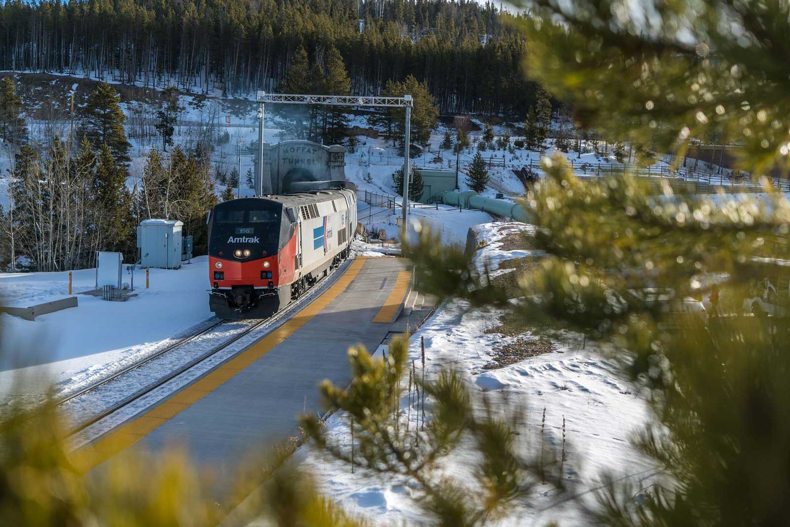 A red-nosed Amtrak train travels through a snow landscape