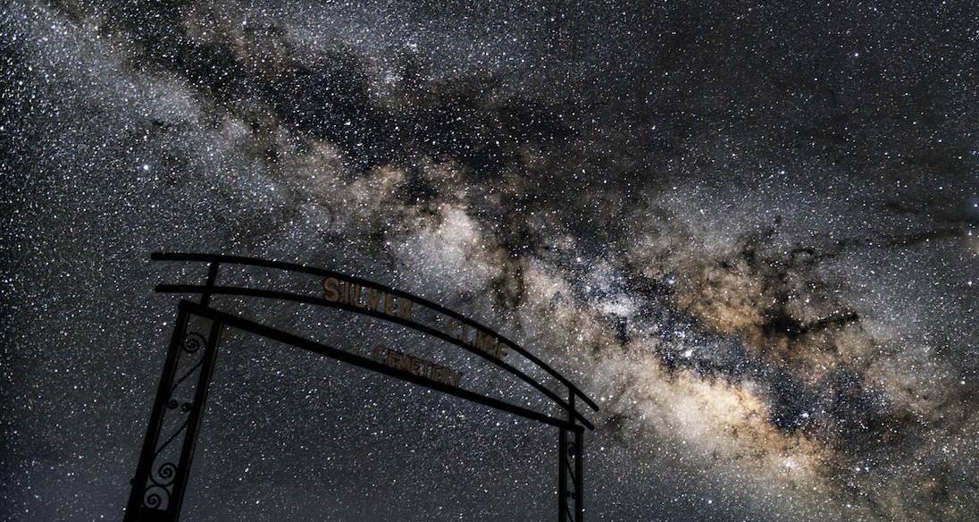 Thousands of stars at night behind a gate to the Silver Cliff cemetery