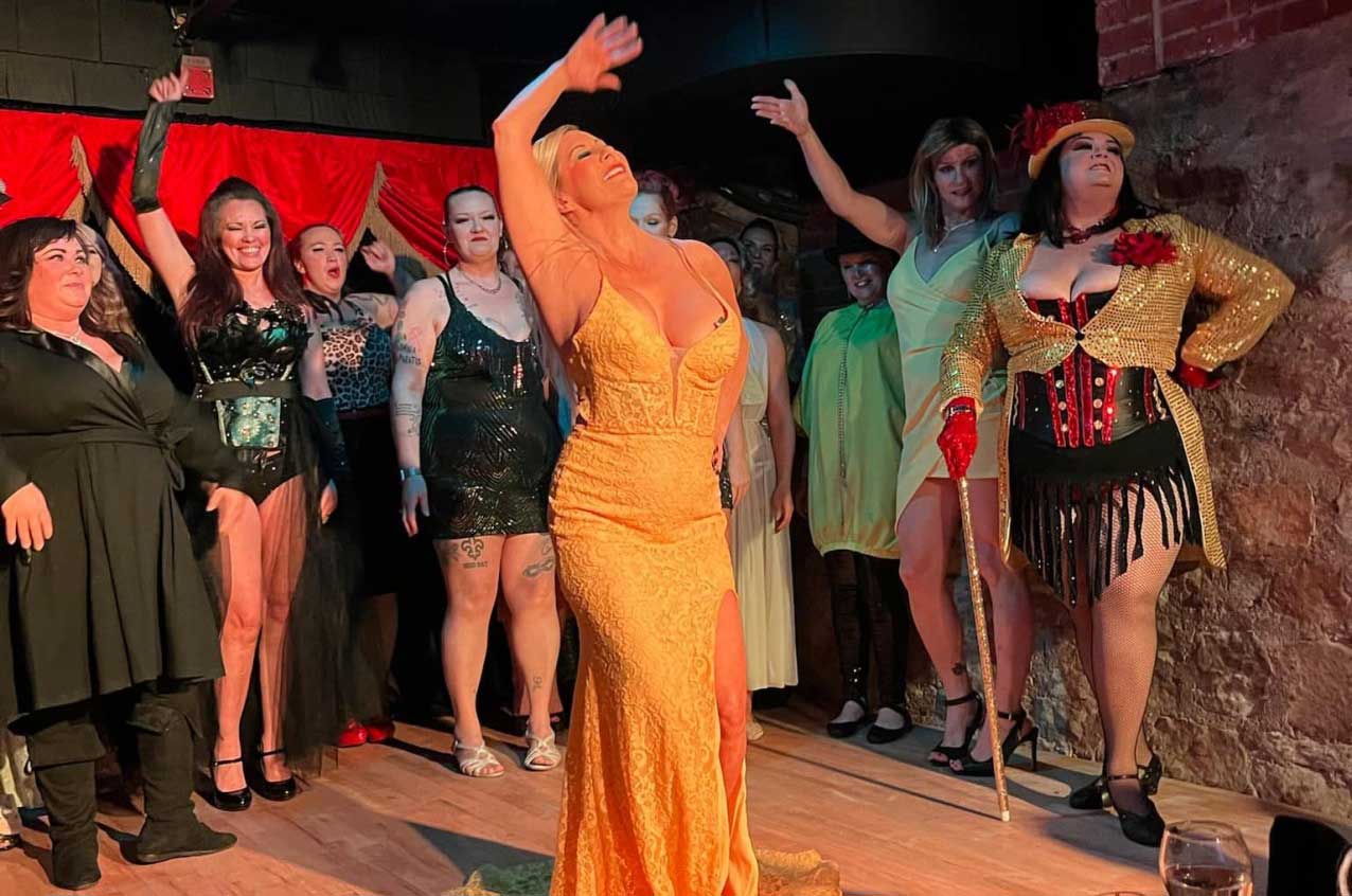 A group of cabaret dancers soak in the applause from a stage
