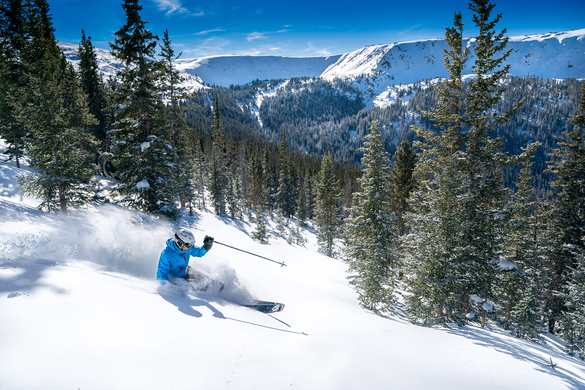 Snow flies through the air as a skier whooshes down the slopes at Winter Park Resort in Colorado.